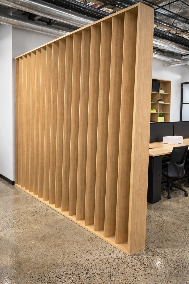 Architectural slat partition wall creating separation between desks and breakout zone